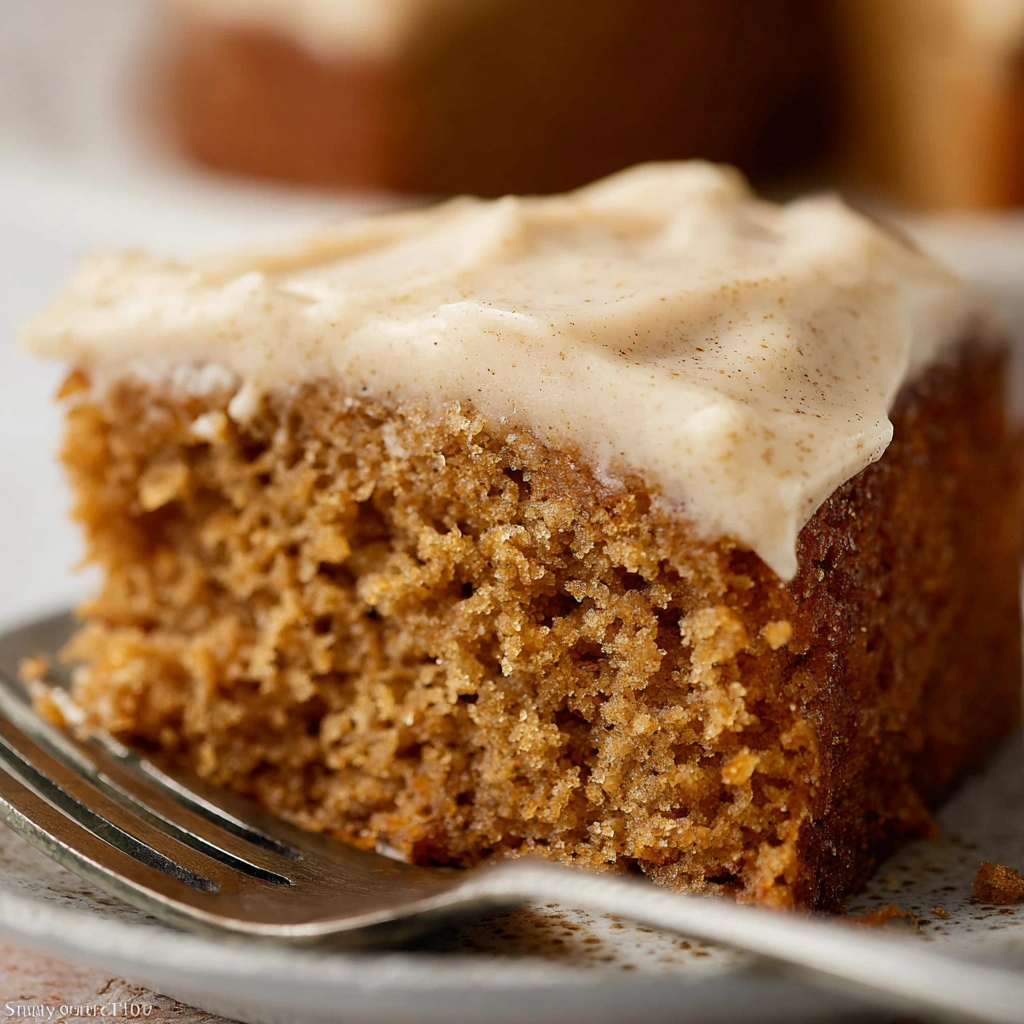 A slice of super moist spice cake topped with frosting and cinnamon.